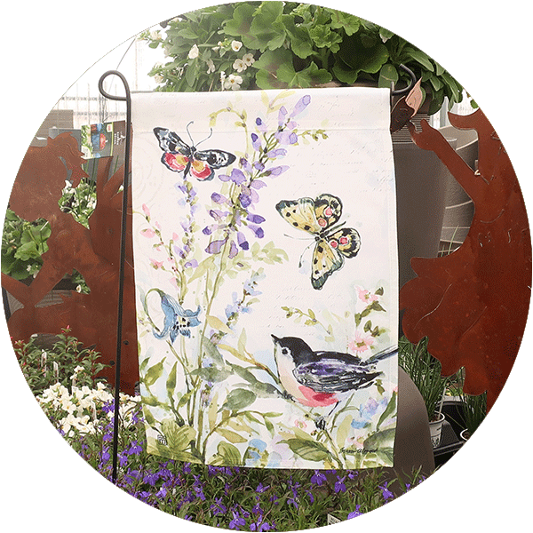 A white garden flag with butterflies and birds on it.